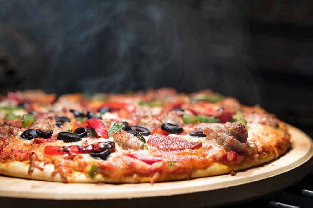 Best Chicago Pizza A sizzling hot supreme pizza with an array of toppings including pepperoni, sausage, black olives, green peppers, and onions, with melted cheese, on a wooden pizza tray
